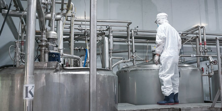 RITA technician monitoring production tanks in cleanroom gear