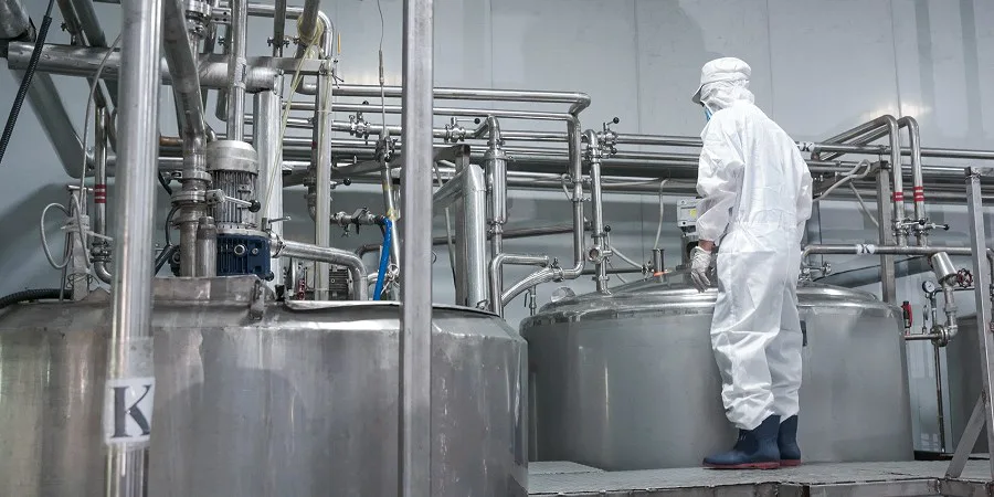 RITA technician monitoring production tanks in cleanroom gear